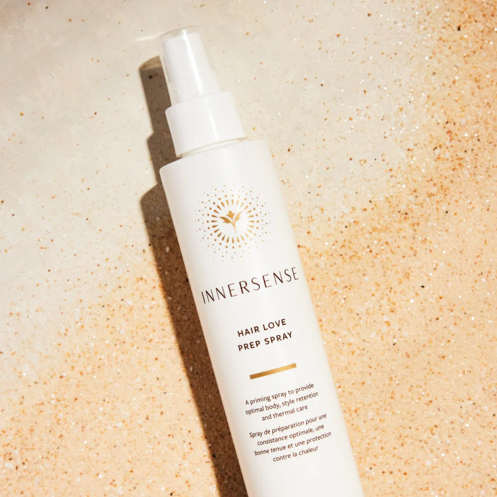 White Innersense Hair Love Prep Spray bottle with gold logo on sandy background.