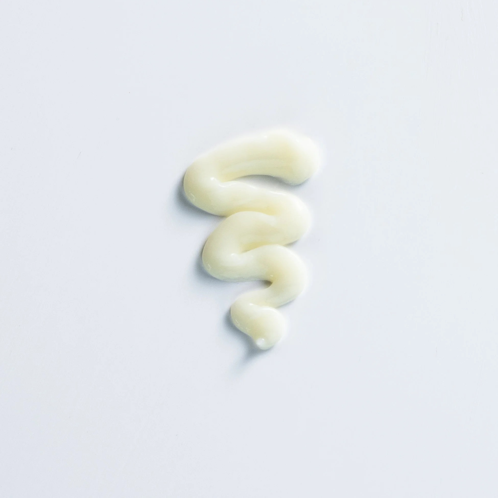 Swirl of light yellow Curly Girl Movement Moisture Conditioner on a white background.