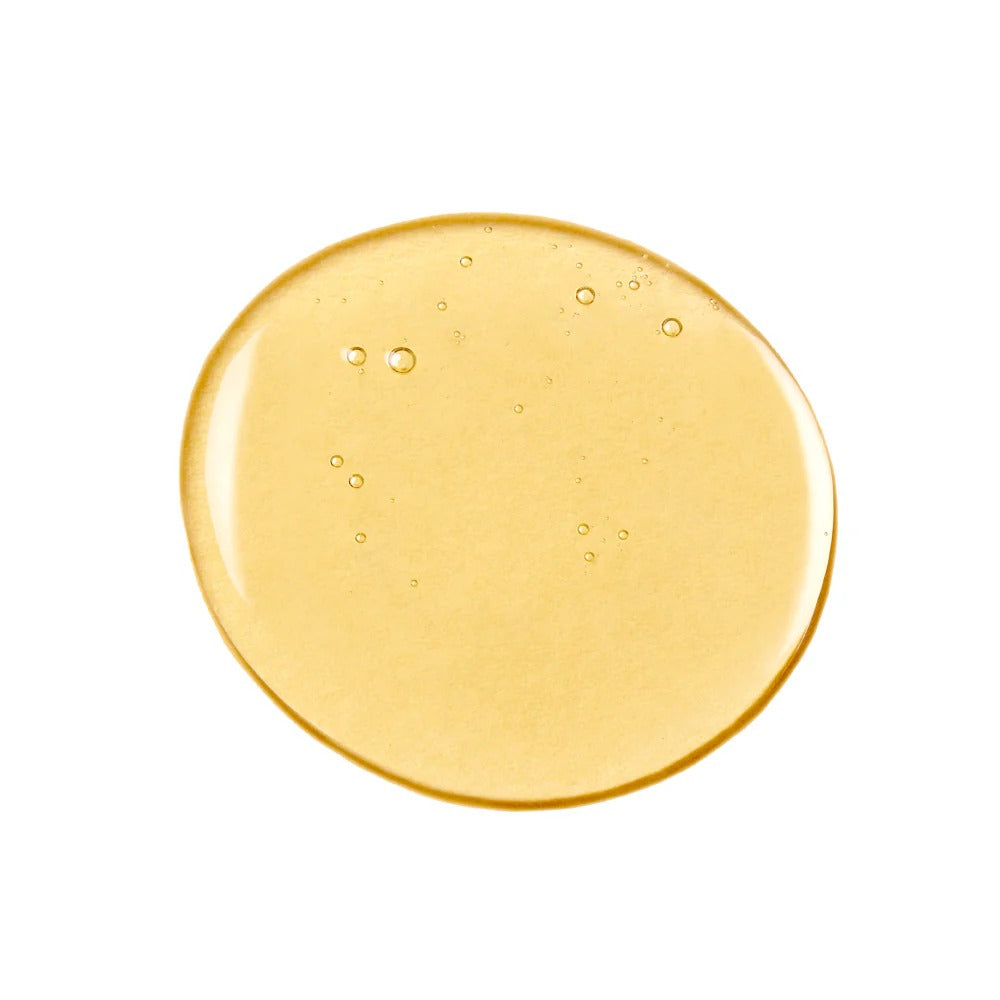 Golden-yellow, translucent drop of Innersense Pure Harmony Hairbath with small bubbles, isolated on white.
