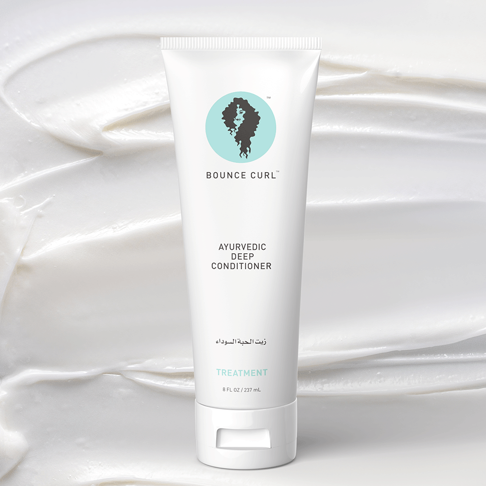 White Bounce Curl Ayurvedic Deep Conditioner tube with light blue and black logo on a creamy white swirl background.