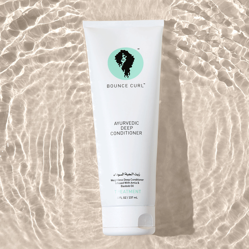 White Bounce Curl Ayurvedic Deep Conditioner tube with a mint green logo, 8 fl oz / 237 mL, on a rippled water background.