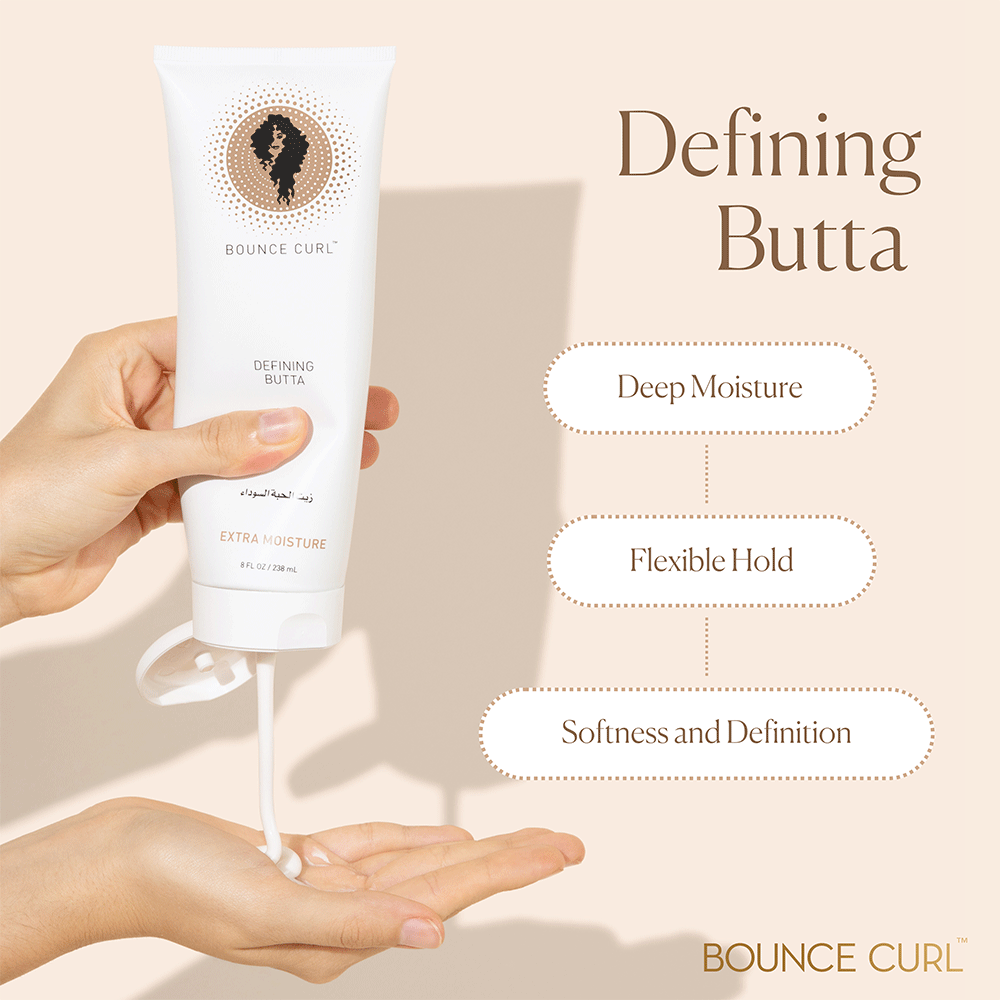 Hands squeezing white Bounce Curl Defining Butta tube, dispensing cream onto a palm.
