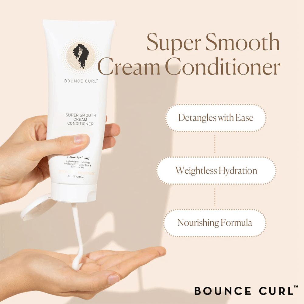 Hand squeezing white Bounce Curl Super Smooth Cream Conditioner from a tube, showing its creamy texture.