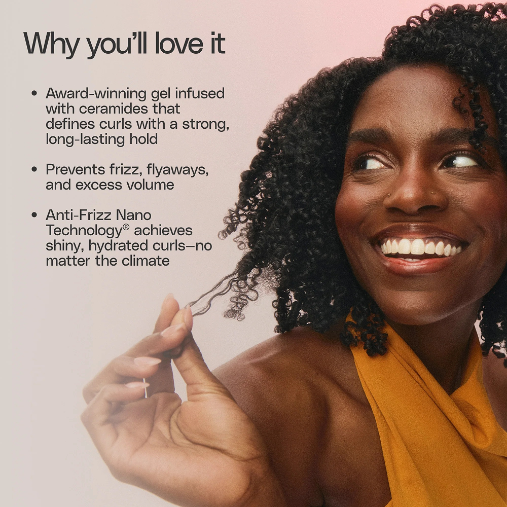 Smiling woman with defined, dark curly hair, holding a strand, against a pink background with product benefits.