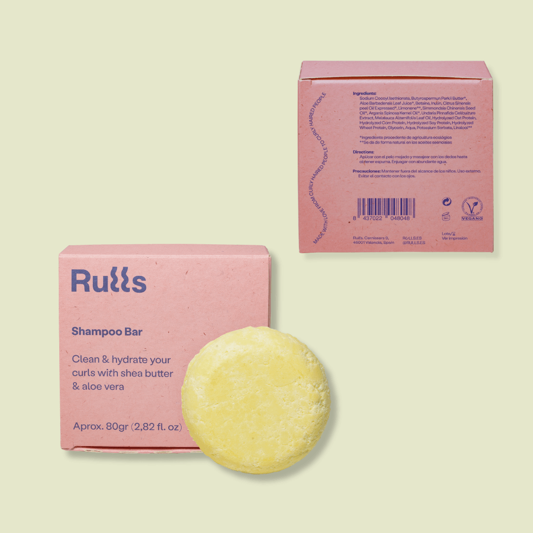 Rulls Solid Shampoo Bar in light yellow, next to its pink paper packaging with product details.