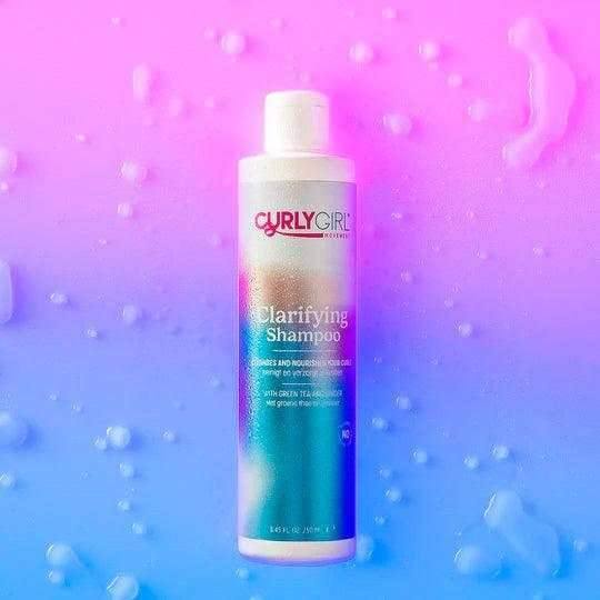 Curly Girl Movement Clarifying Shampoo 250ml bottle with colorful label, on a pink and blue background with water drops.